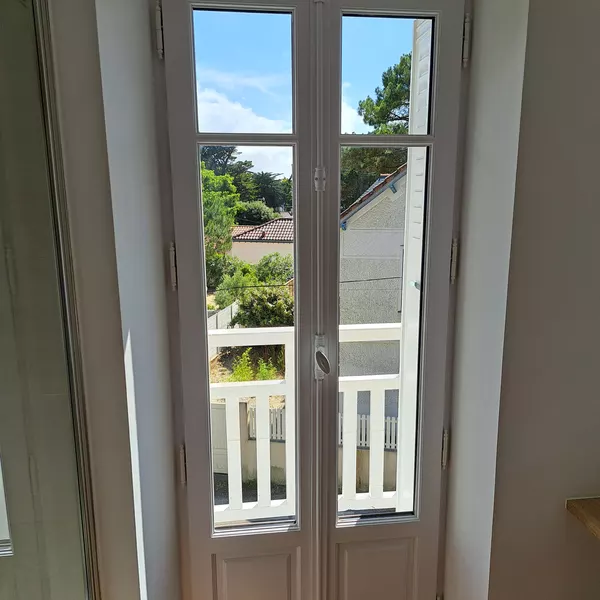 Porte-fenêtre deux vantaux à petits bois donnant sur un balcon (juillet 2024)